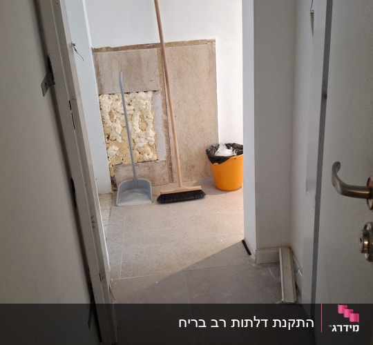 דלת פתוחה עם ידית מתכת ובריחים גלויים